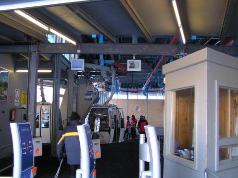 Gondola kabinos lift alapállomása, balra pedig a "kabingarázs" a plafonon kígyózó függesztő sínekkel.